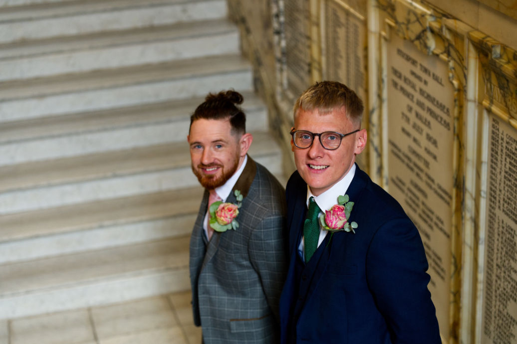 Groom and best man smile as they see the   bride for the first time at a stockport town hall registry wedding  